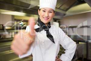 Smiling female cook gesturing thumbs up in kitchen