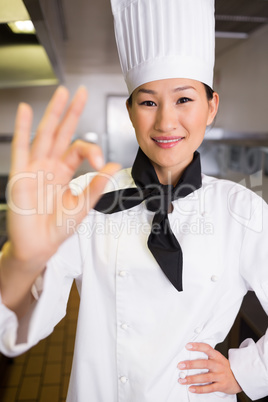 Smiling female cook gesturing okay sign in kitchen