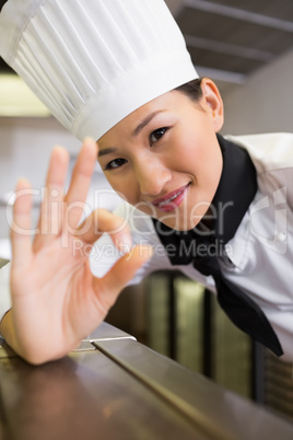 Smiling female cook gesturing okay sign in kitchen
