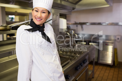 Smiling female cook standing in kitchen