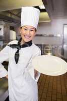 Smiling female cook holding an empty plate in kitchen