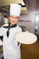 Female cook holding an empty plate in kitchen
