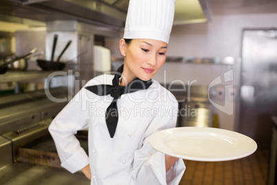 Female cook holding empty plate in kitchen