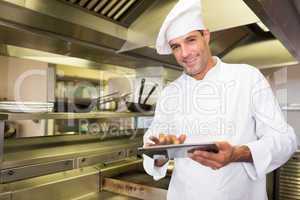 Smiling male cook using digital tablet in kitchen