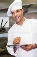 Smiling male cook using digital tablet in kitchen