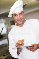 Smiling male cook using digital tablet in kitchen