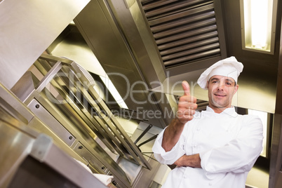 Smiling male cook gesturing thumbs up in kitchen