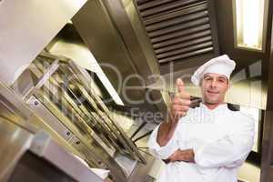 Smiling male cook gesturing thumbs up in kitchen