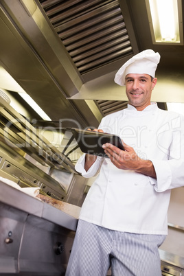 Smiling male cook using digital tablet in kitchen