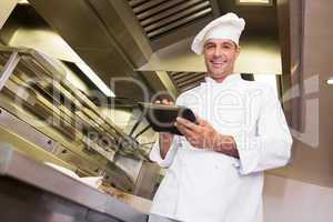 Smiling male cook using digital tablet in kitchen