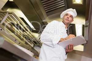 Serious male cook with clipboard in kitchen
