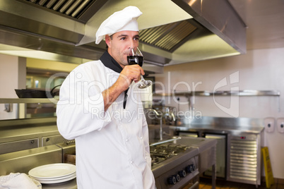 Male cook drinking red wine in kitchen