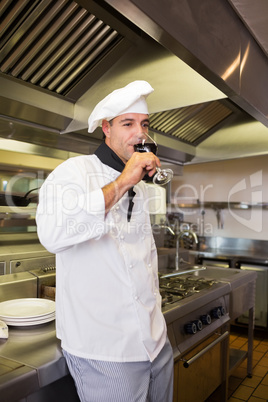 Male cook drinking red wine in kitchen