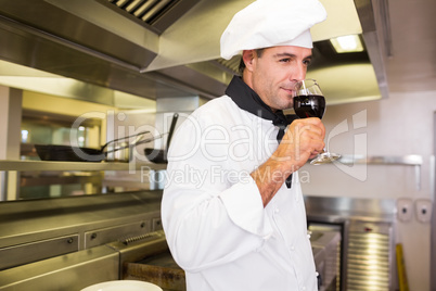 Male cook drinking red wine in kitchen