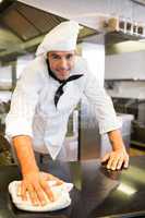 Smiling male cook wiping the counter top in kitchen