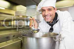 Smiling male cook tasting food in kitchen