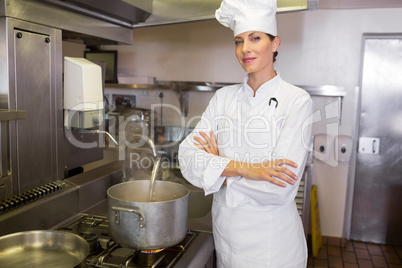 Smiling female cook with arms crossed in kitchen