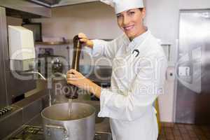 Smiling female cook preparing food in kitchen