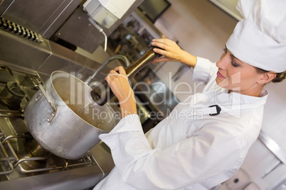 Concentrated female cook preparing food in kitchen