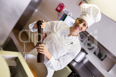 Smiling female cook preparing food in kitchen