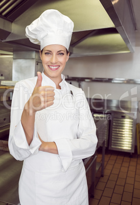 Smiling female cook gesturing thumbs up in kitchen