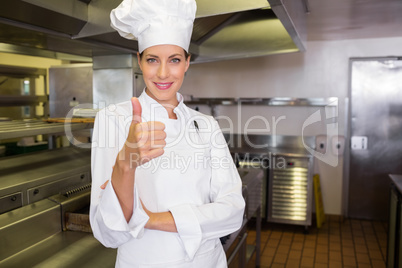 Smiling female cook gesturing thumbs up in kitchen