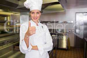 Smiling female cook gesturing thumbs up in kitchen