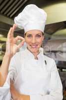 Smiling female cook gesturing okay sign in kitchen