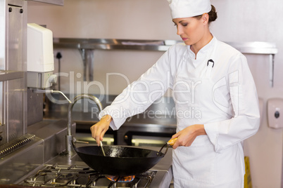 Concentrated female chef preparing food in kitchen