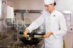 Concentrated female chef preparing food in kitchen