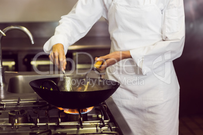 Mid section of a chef preparing food in kitchen