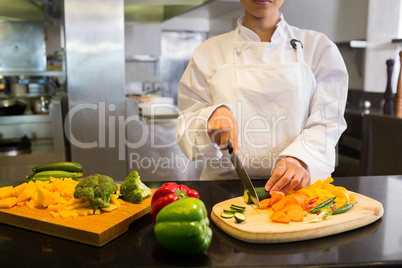 Female chef cutting vegetables in kitchen