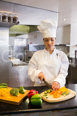 Female chef cutting vegetables in kitchen