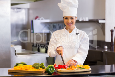 Smiling female chef cutting vegetables in kitchen