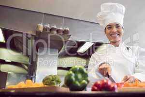 Smiling female chef cutting vegetables in kitchen