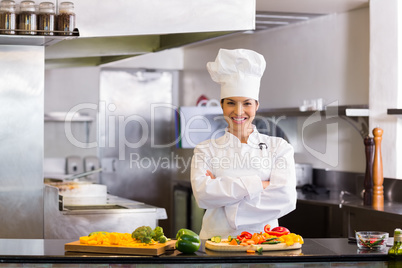 Smiling female chef with cut vegetables in kitchen