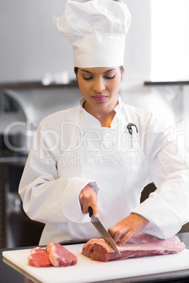 Female chef cutting meat in kitchen