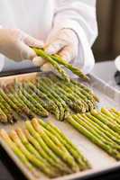 Hands with fresh asparagus in kitchen
