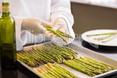 Hands with fresh asparagus and oil in kitchen