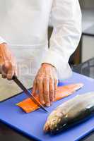 Closeup mid section of a chef cutting fish