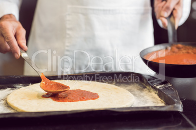 Mid section of a male chef preparing pizza