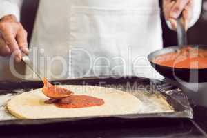 Mid section of a male chef preparing pizza