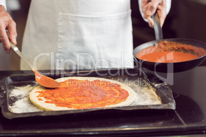 Mid section of a male chef preparing pizza