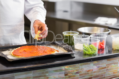 Mid section of chef garnishing food in kitchen