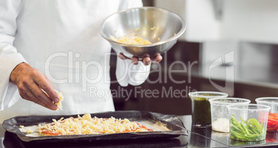 Mid section of a chef garnishing food in kitchen