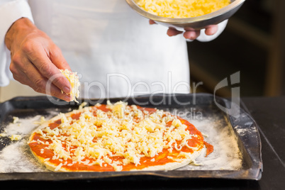 Closeup mid section of a male chef preparing pizza in kitchen