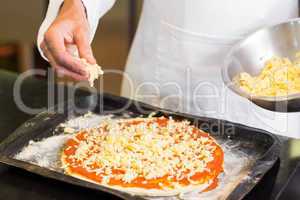Mid section of a chef preparing pizza