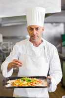 Confident chef holding cooked food in kitchen