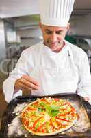 Confident chef holding cooked food in kitchen