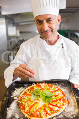 Confident male chef holding cooked food in kitchen